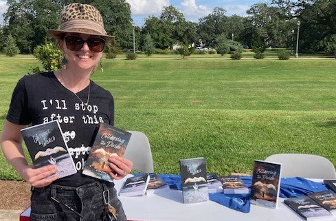 Kirsten Illarmo holding books in front of a field. 